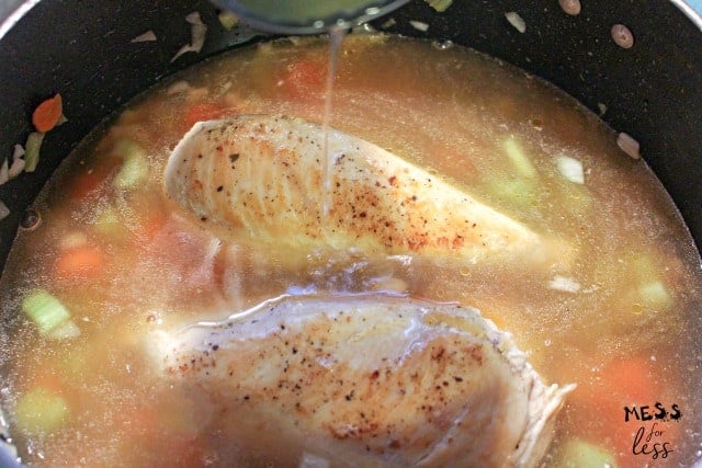 chicken cooking in broth in a pot