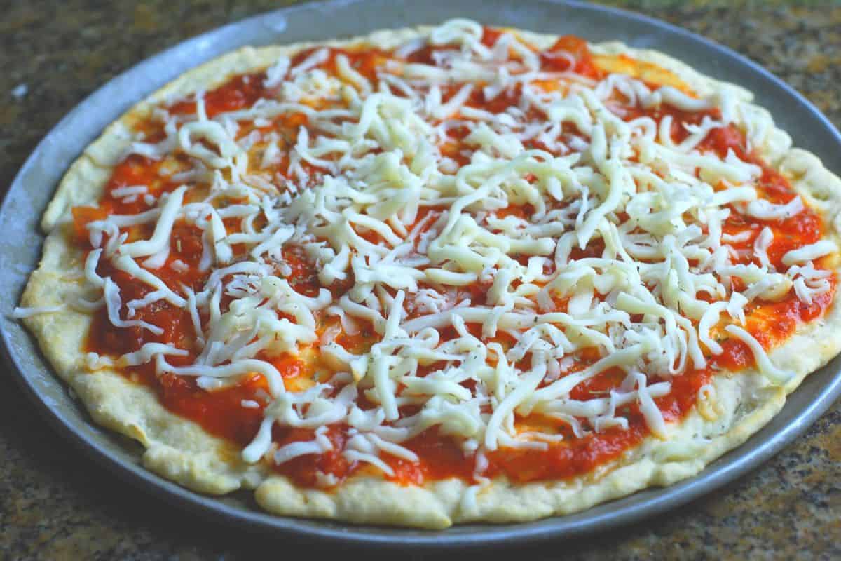 pizza dough with sauce and shredded mozzarella