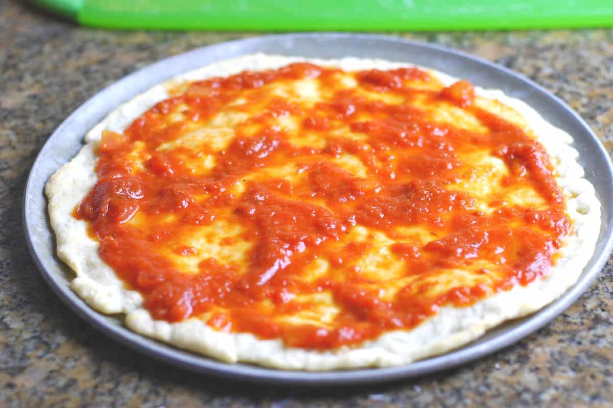 pizza dough in pan with sauce