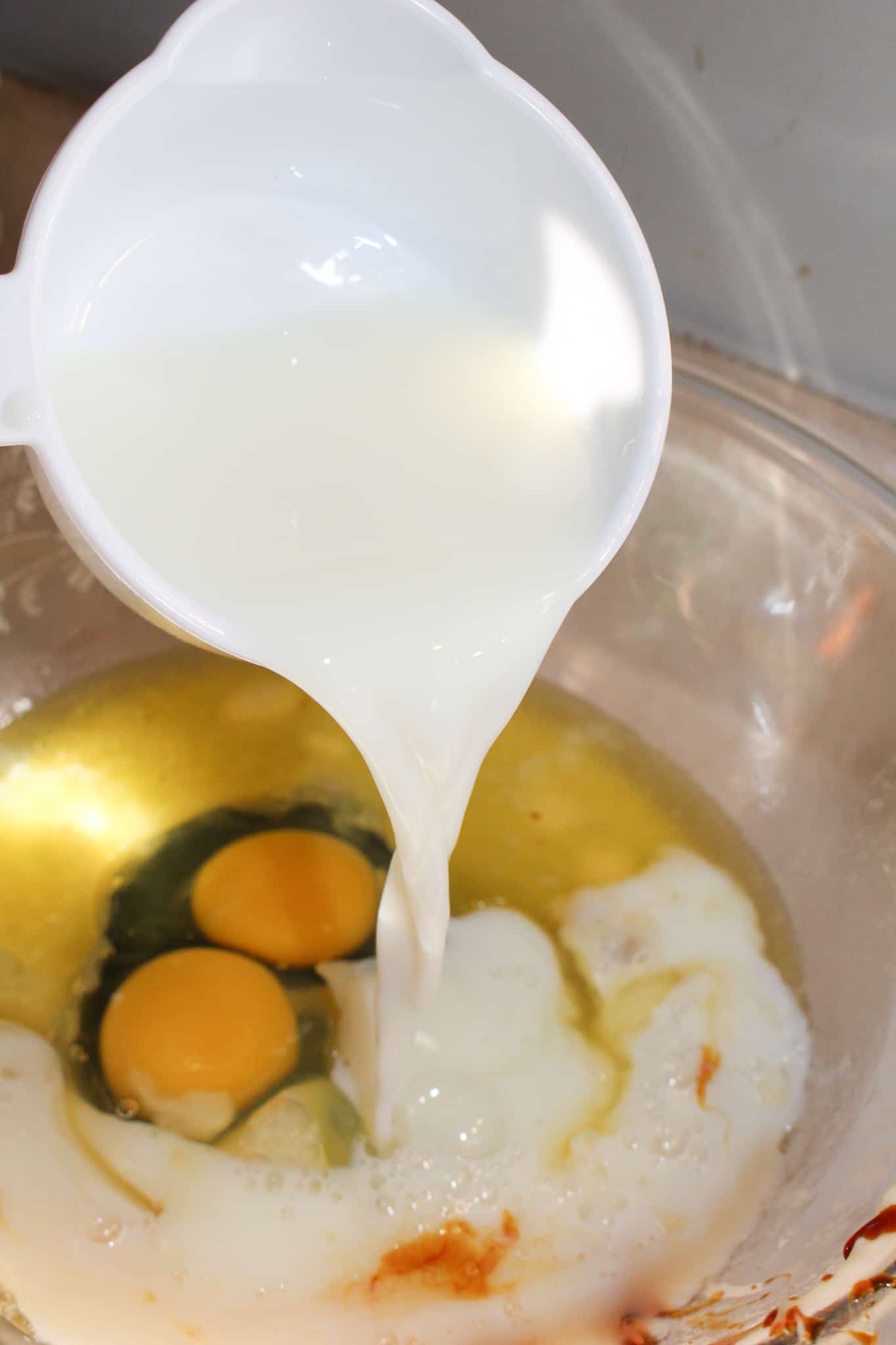 pouring milk into a bowl with eggs