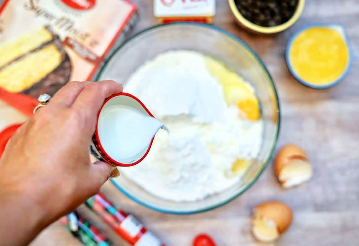 pouring milk to cake batter in a bowl.