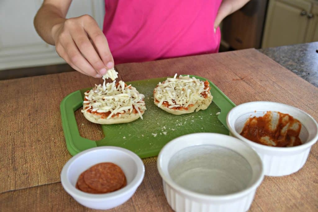 putting cheese on english muffin pizzas