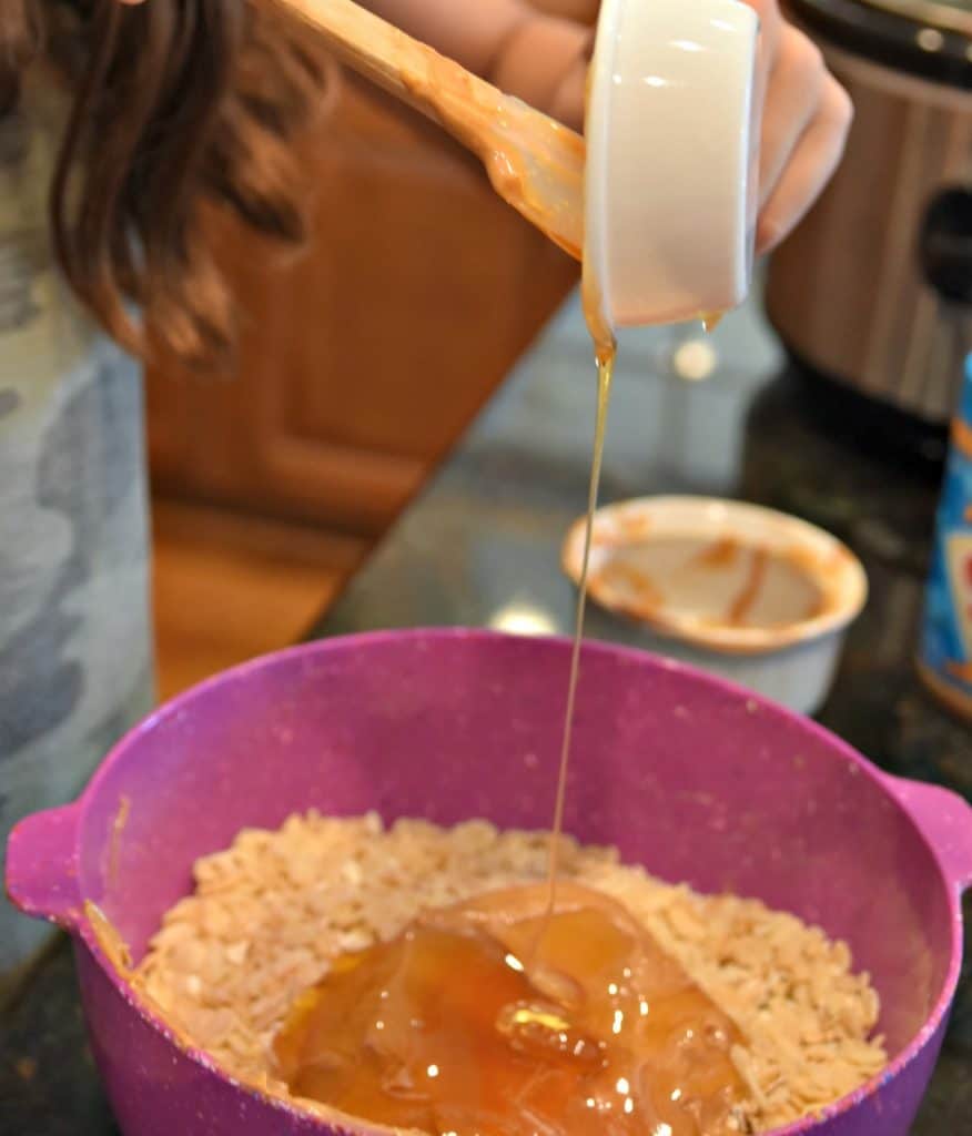 pouring honey into a bowl with rice krispies peanut butter and oats