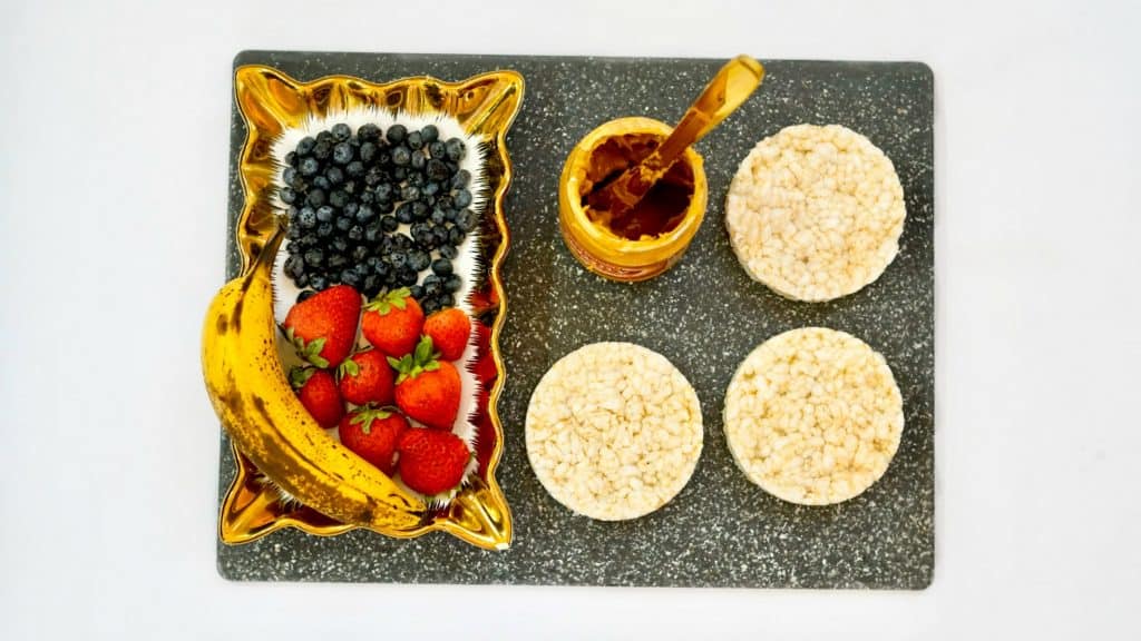 rice cakes and peanut butter and fruit on a cutting board