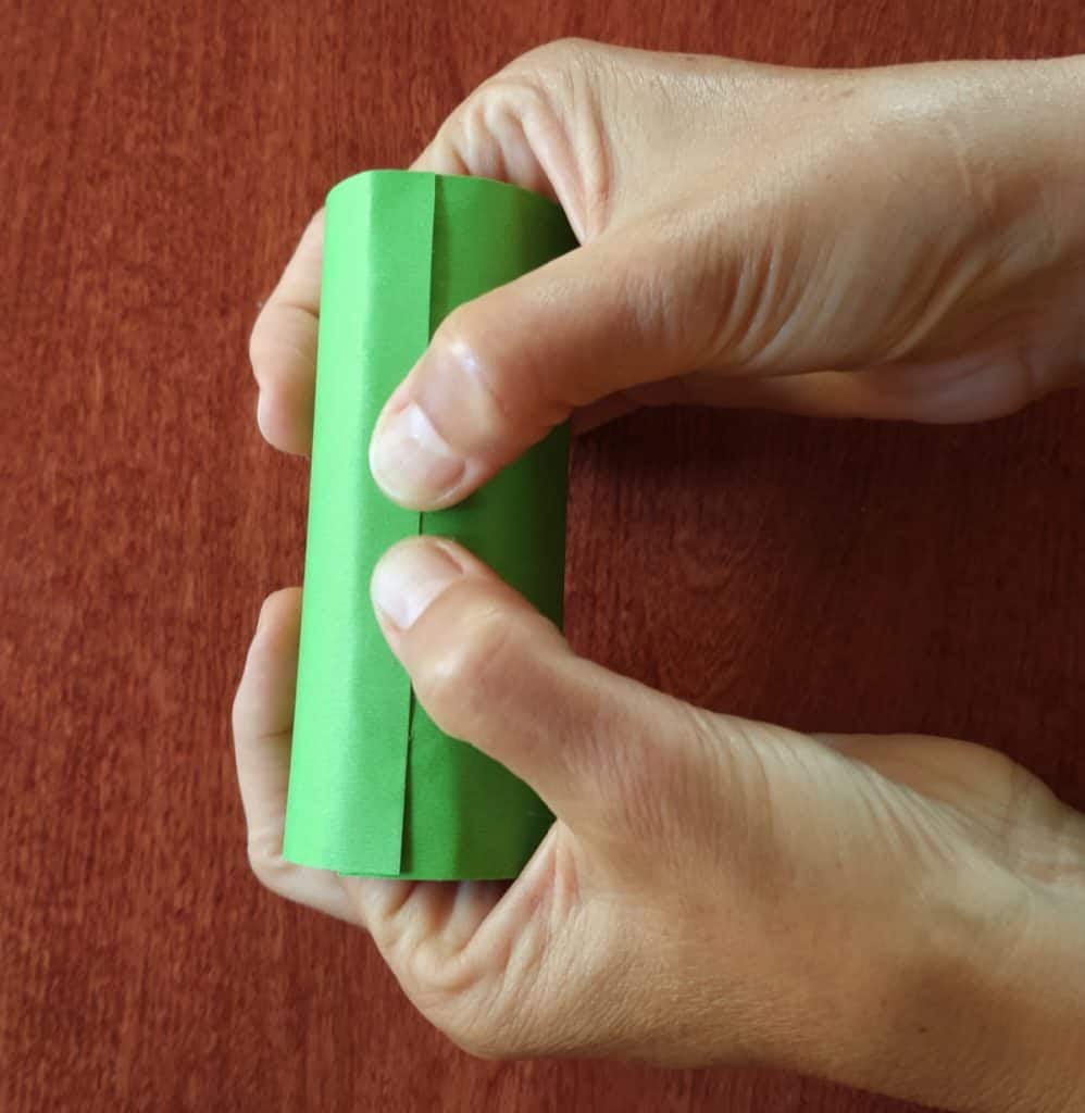 hand holding green paper in cylinder