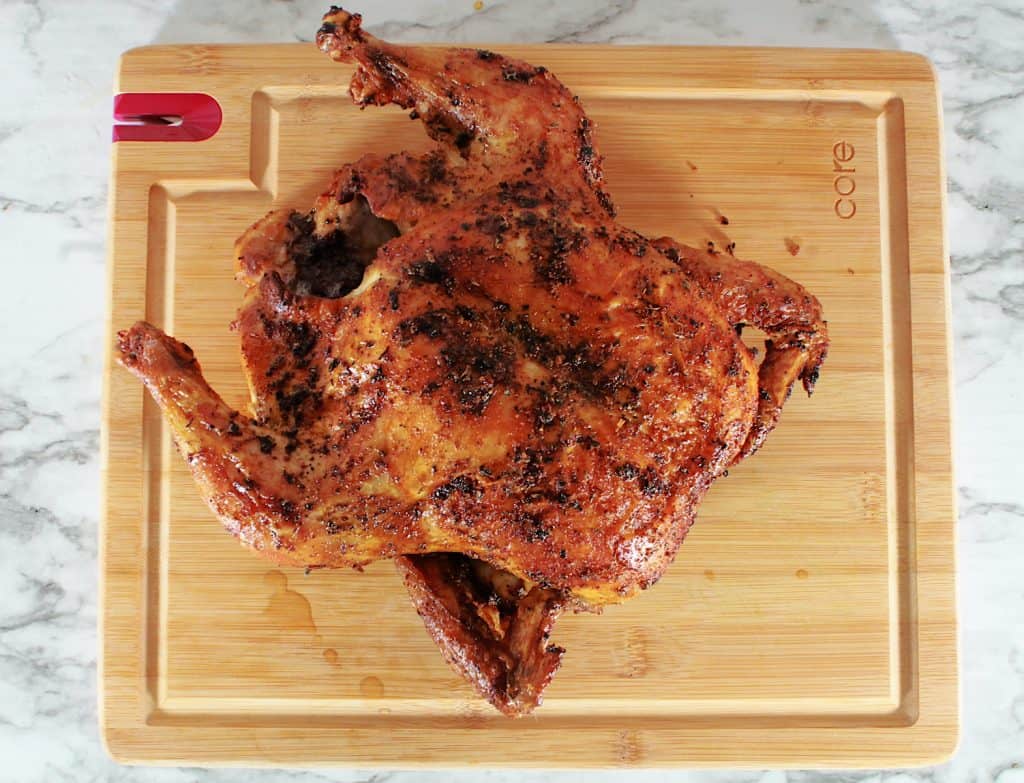 whole cajun roast chicken on cutting board