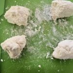 4 balls of dough on green cutting board