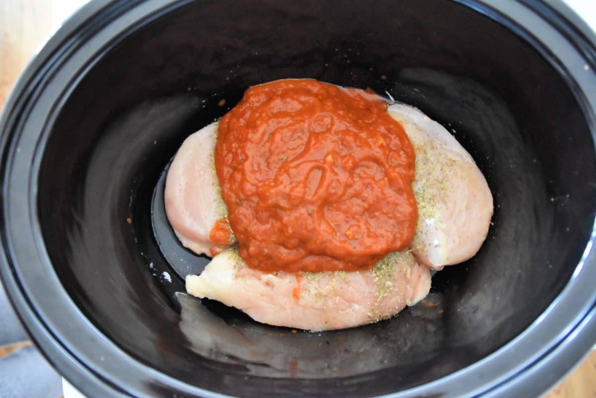 raw chicken with sauce in a crock pot