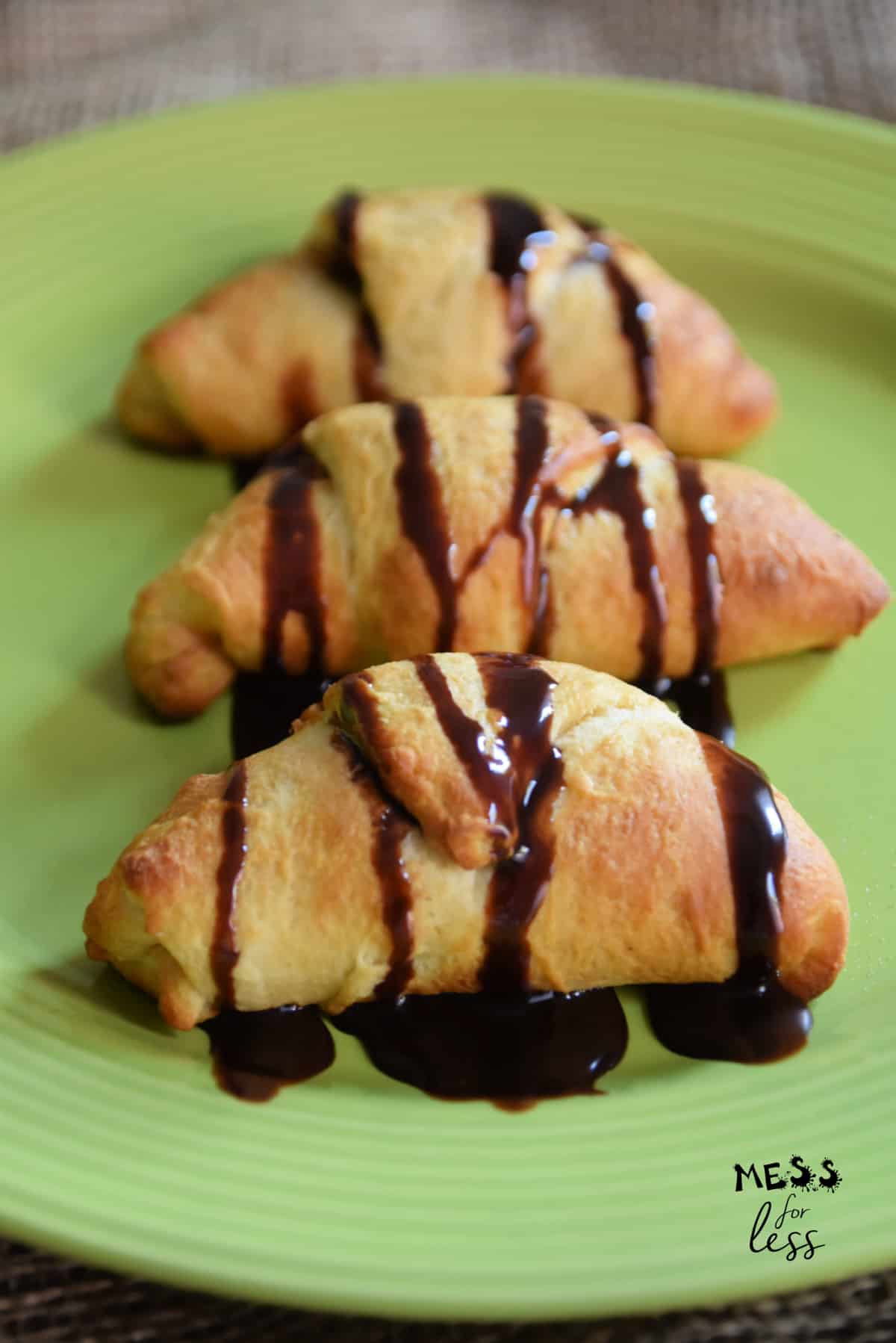 three peanut butter chocolate crescent rolls drizzled with chocolate on a green plate