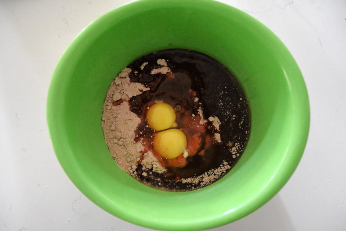 red velvet cake mix, oil and two eggs in a green bowl