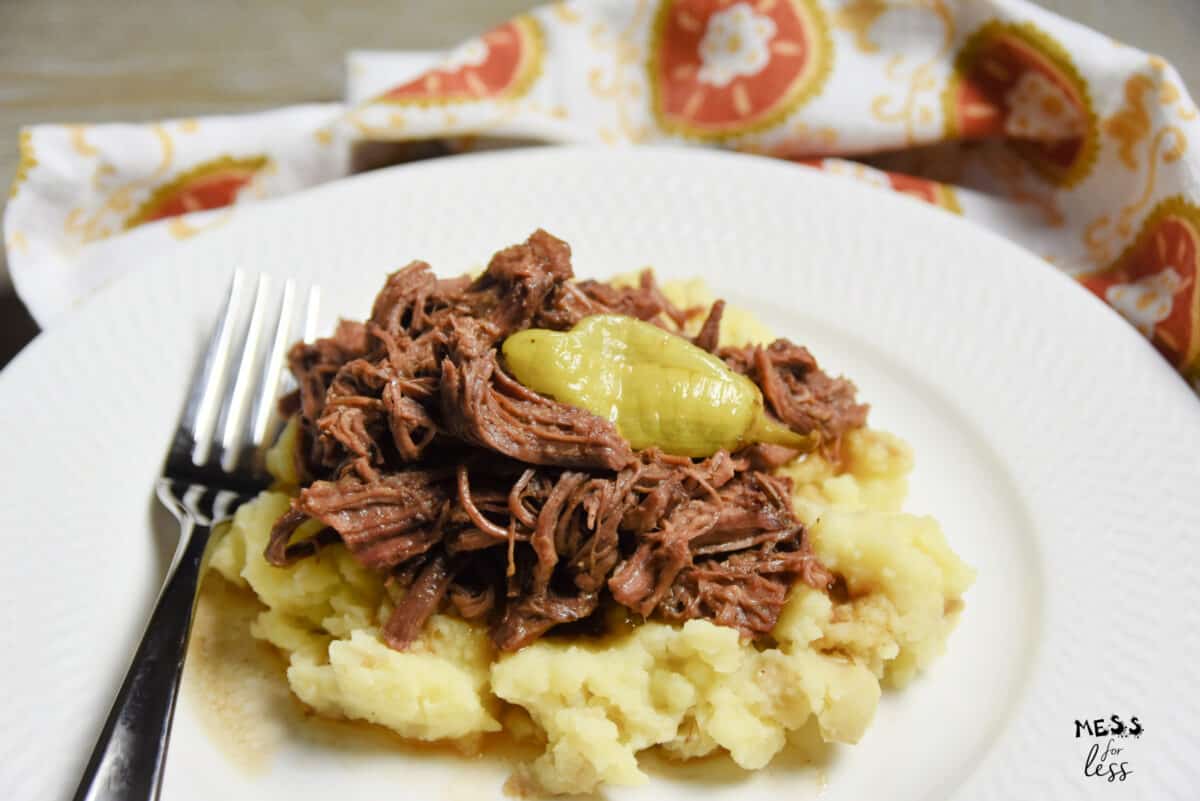 roast with pepperoncini on a plate with mashed potatoes