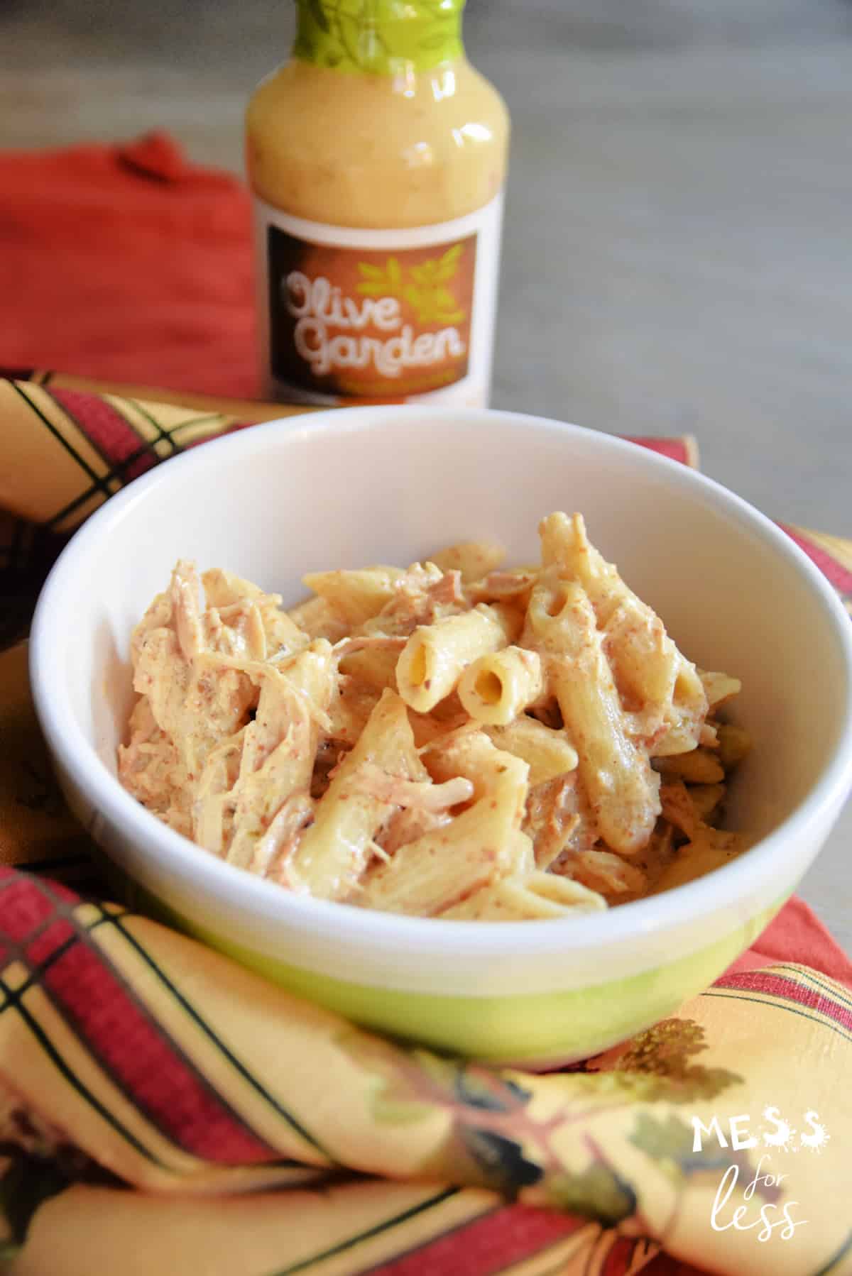 chicken and pasta in a bowl with a bottle of olive garden dressing in the background