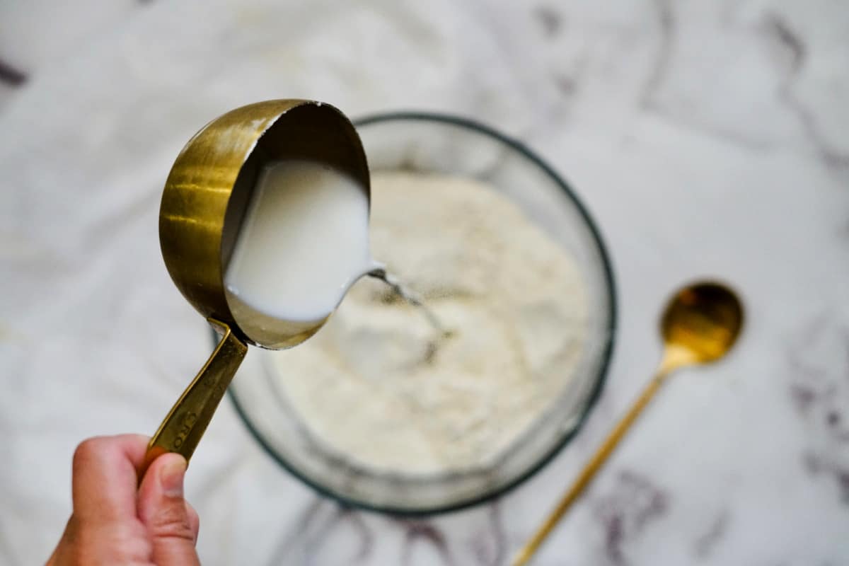 pouring milk into pancake batter to make pancake muffins