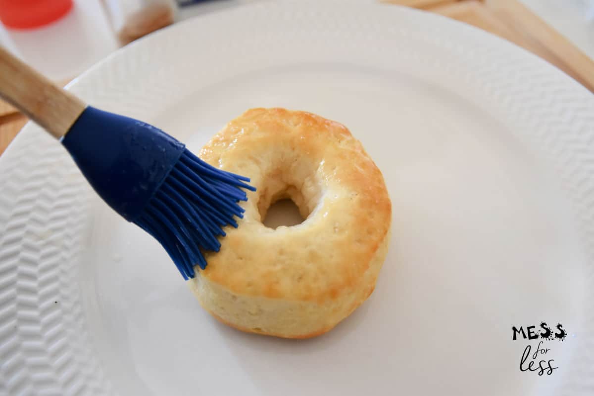 brushing melted butter on a donut
