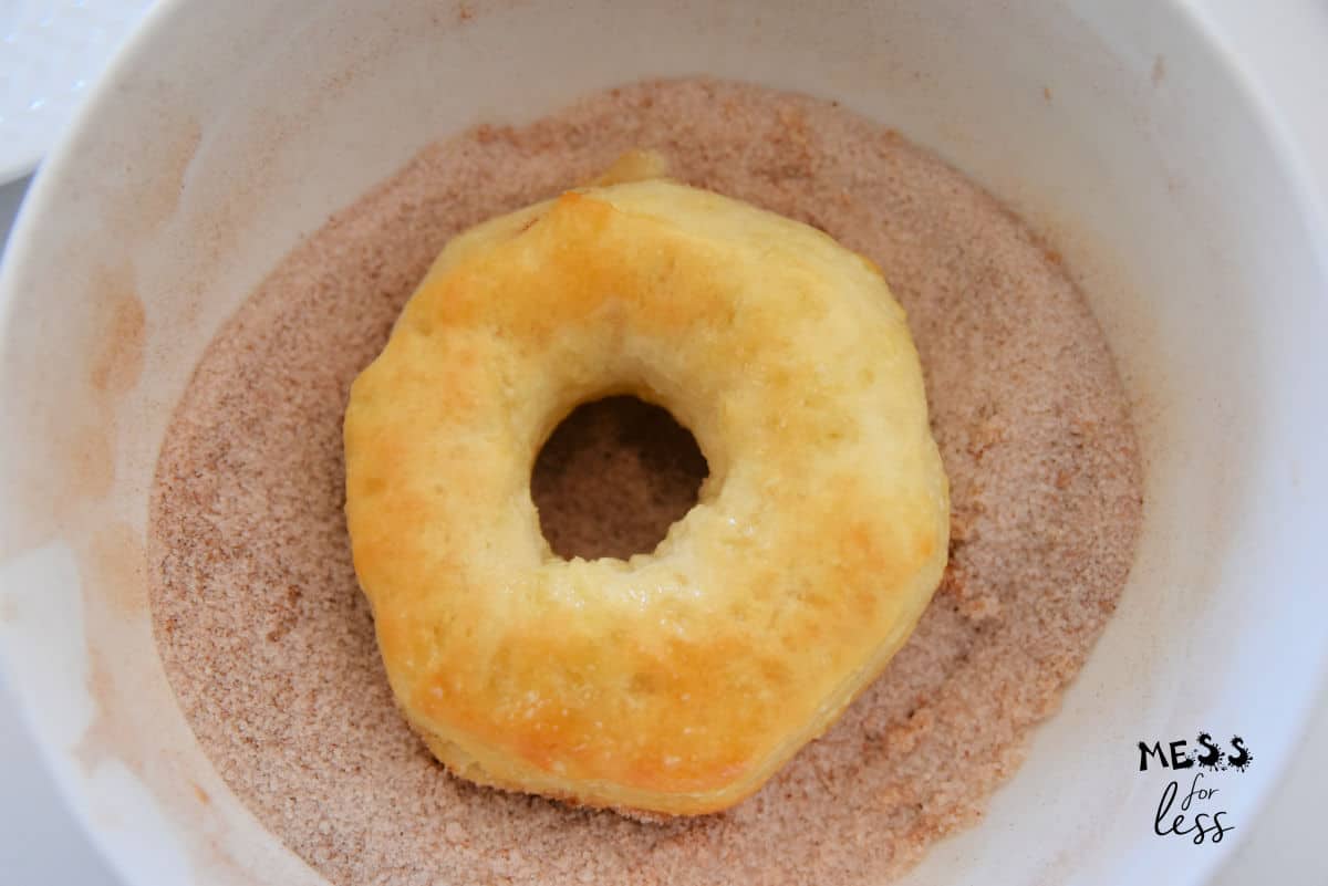 baked donut in a bowl of cinnamon sugar