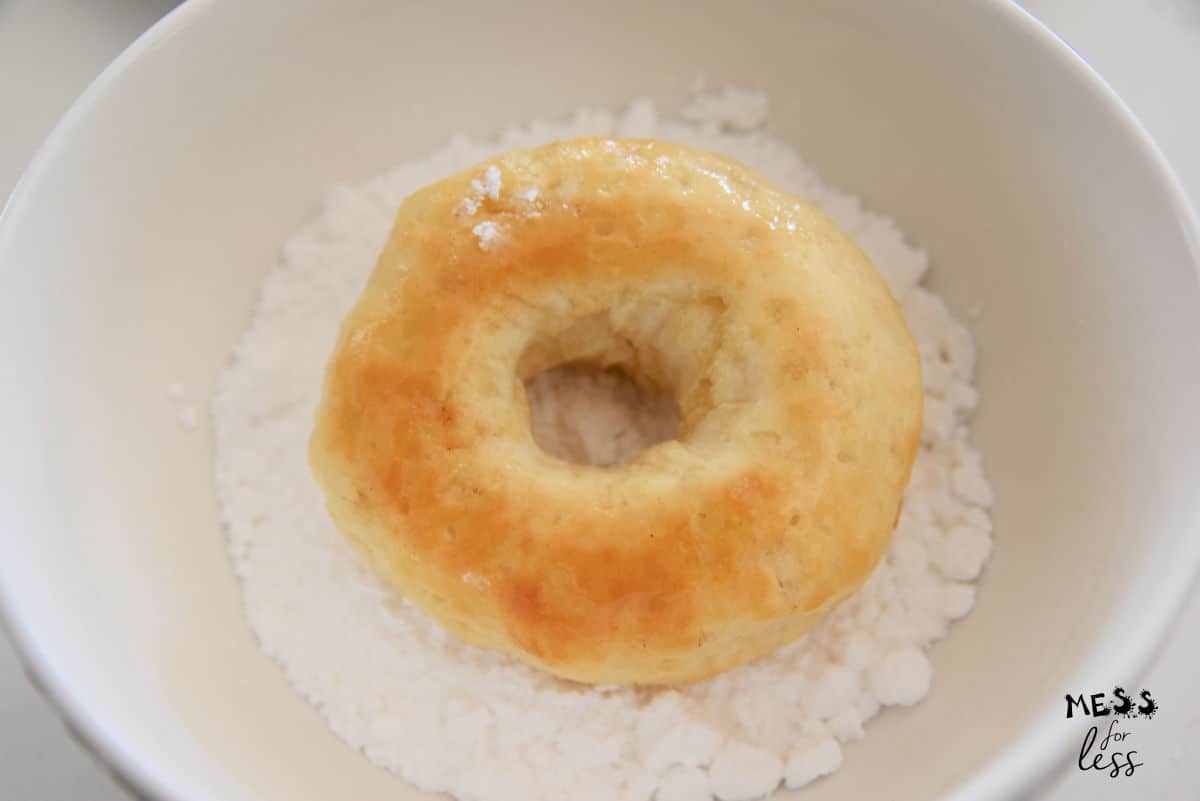 baked donut in a bowl of powdered sugar