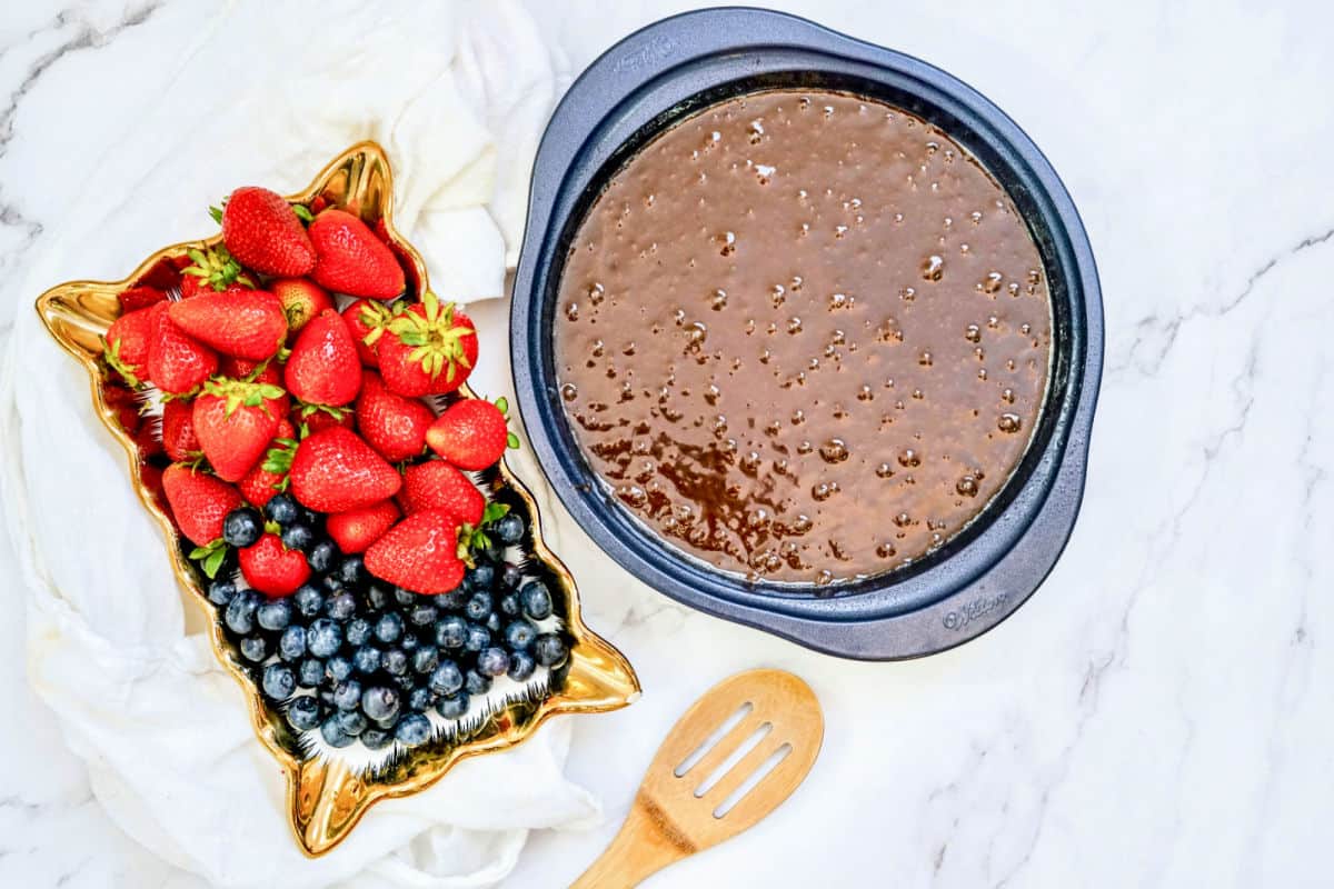 brownie batter in a pan with strawberries and blueberries