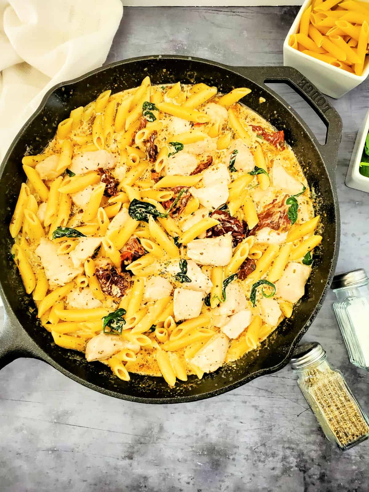 creamy tuscan chicken and pasta in skillet.