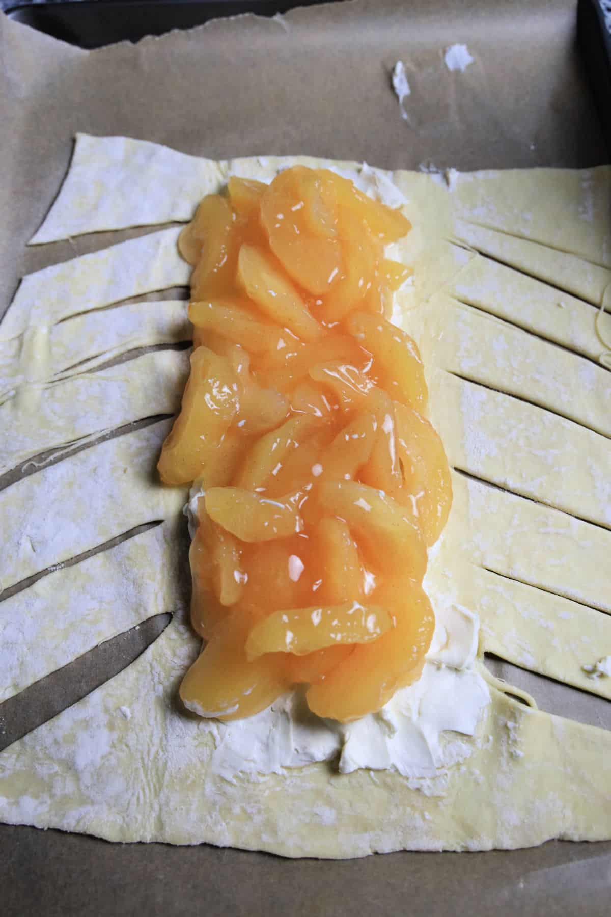 puff pastry dough with slits cut in side with apple pie filling in middle