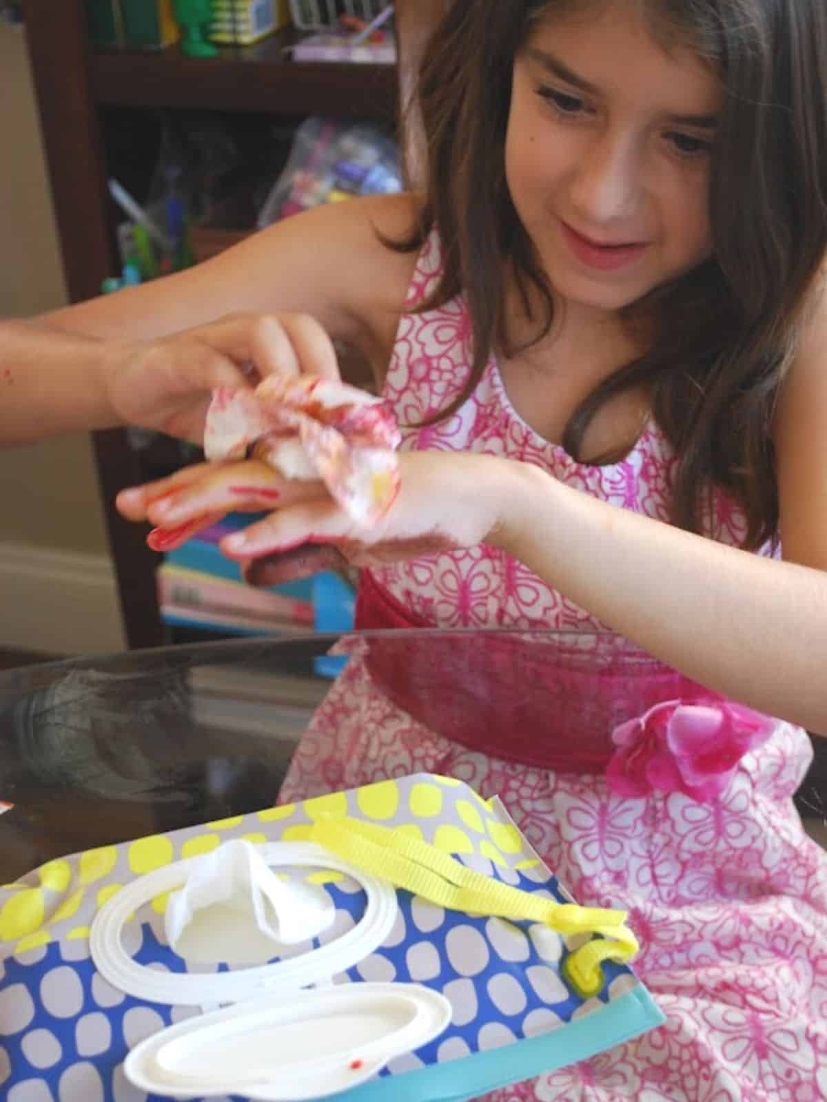 child cleaning hands with baby wipe.