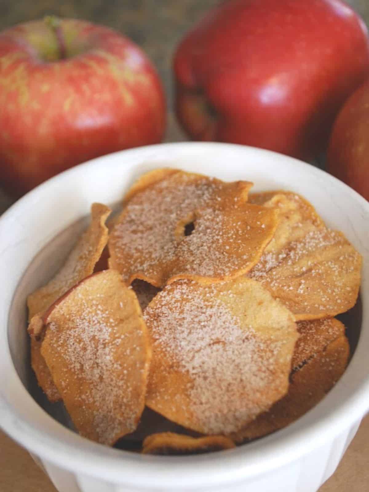apple chips in bowl with red apples in background