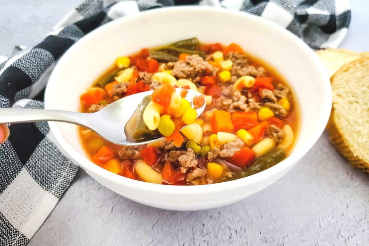 bowl of macaroni beef soup with a spoon.