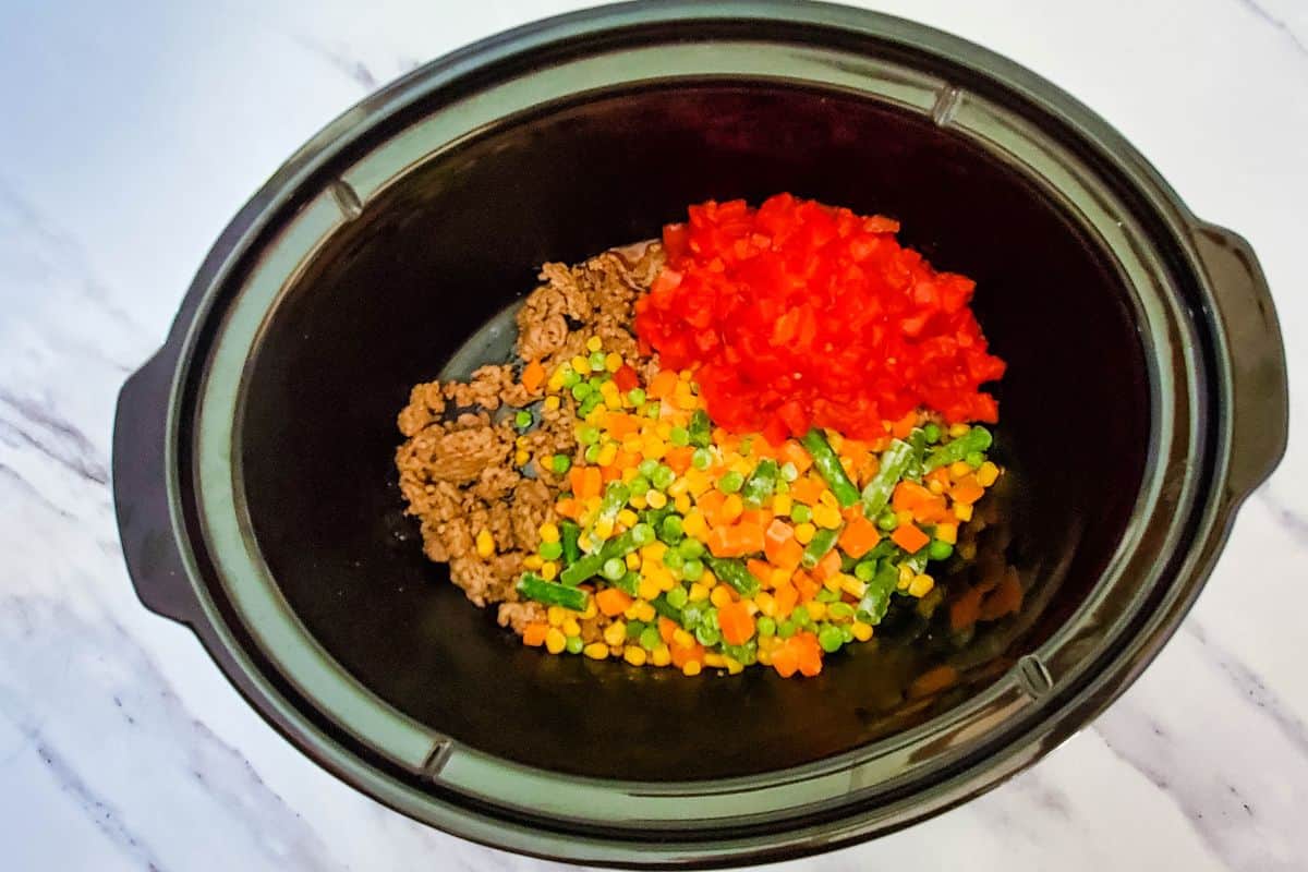 crockpot with beef, veggies, and tomatoes.