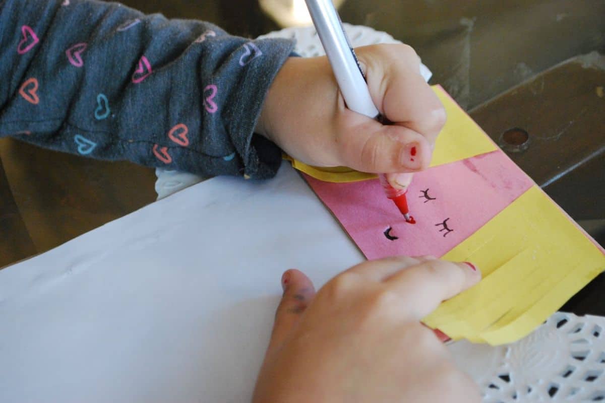 child drawing face on angel craft.