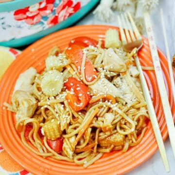 chicken lo mein on plate with utensils