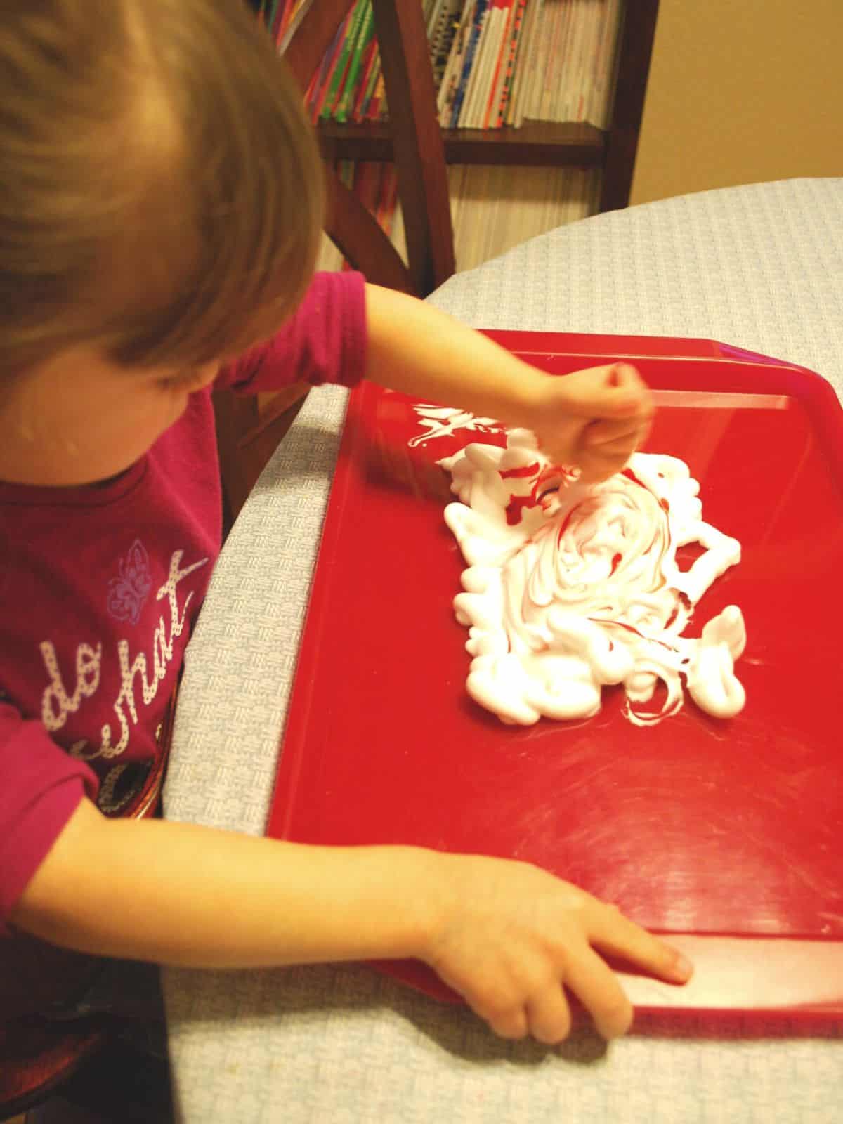 child stirring food coloring into shaving cream