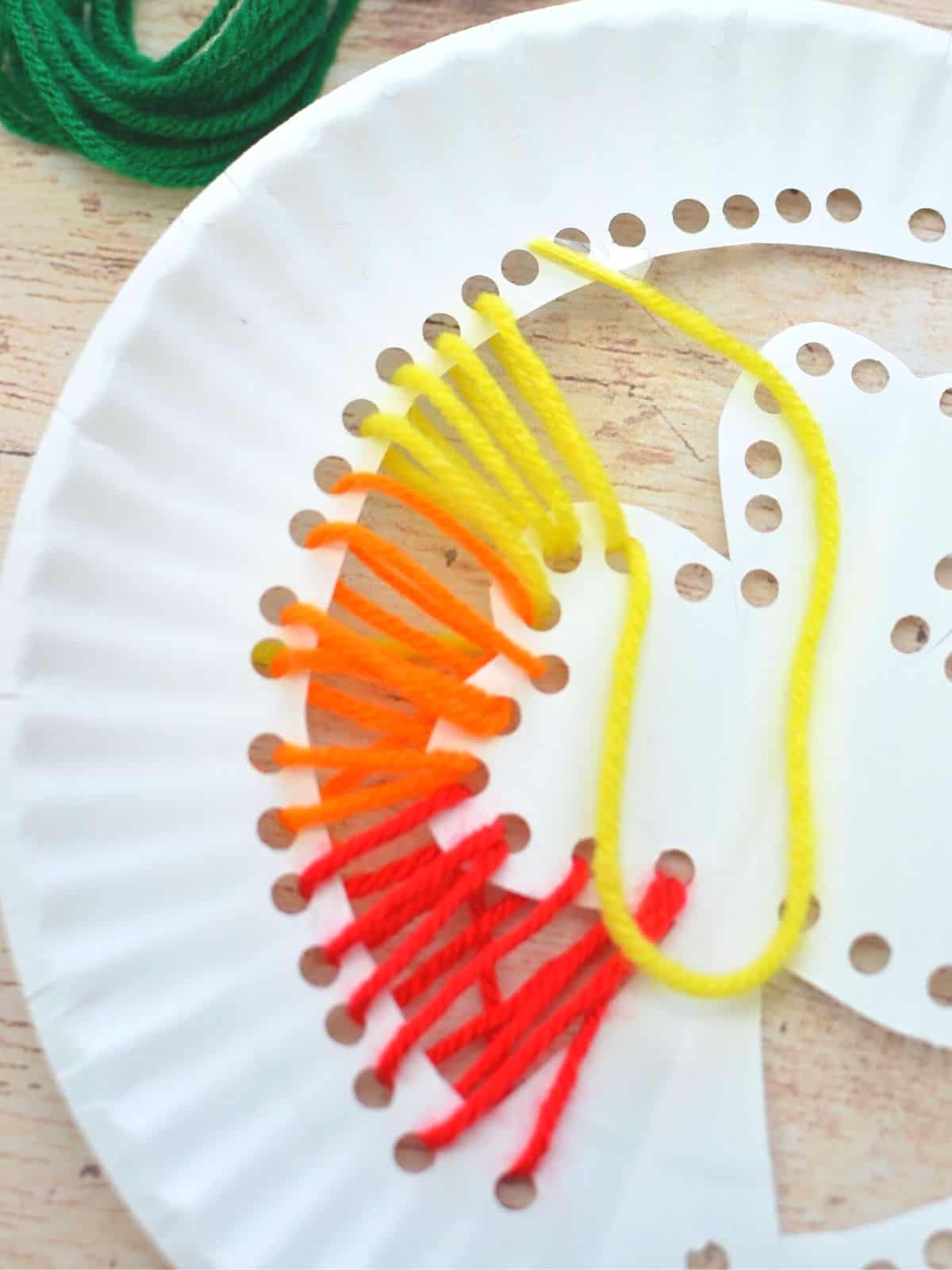 red orange and yellow yarn on paper plate lacing craft