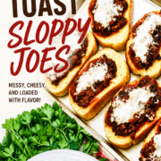 A tray of cheesy Texas Toast Sloppy Joes sits on a red-checked tablecloth, garnished with parsley and ready to serve on white plates.