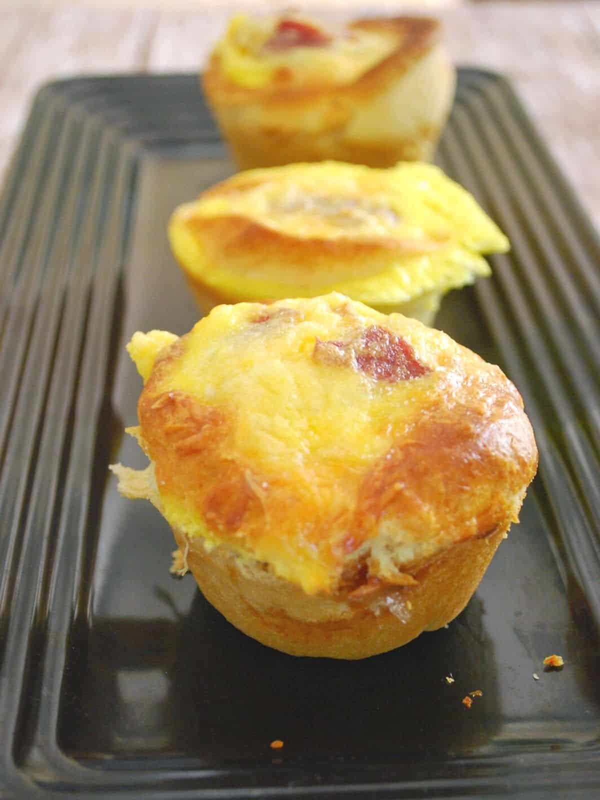 three turkey bacon and egg muffins on plate.