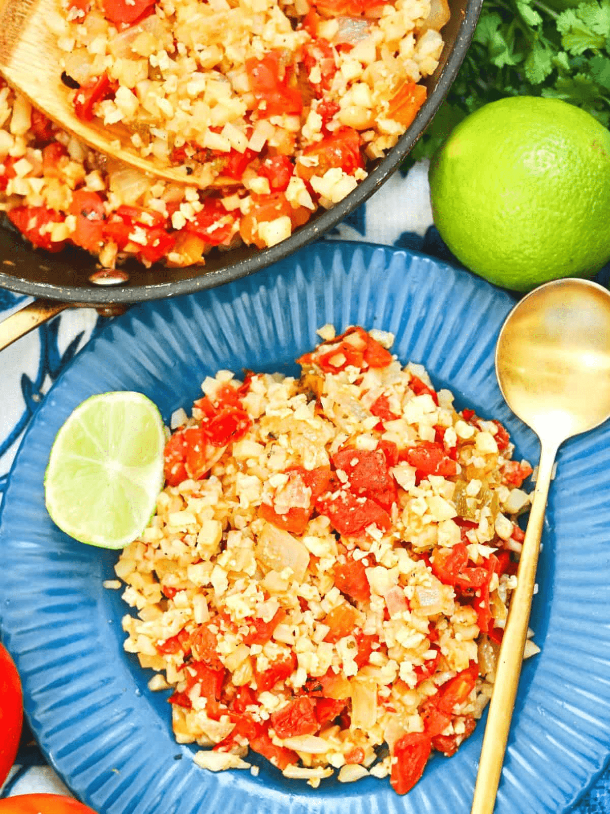 cauliflower rice with tomatoes on blue plate with lime.
