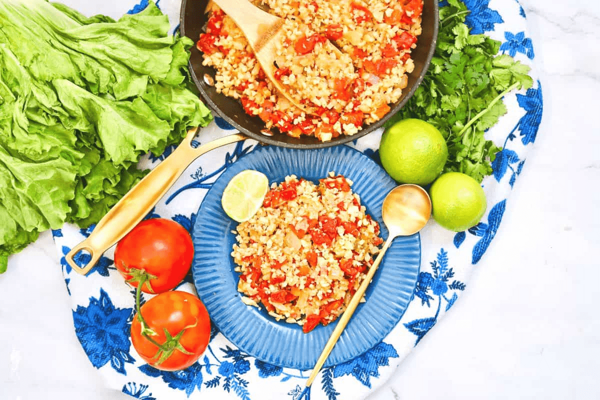 spanish cauliflower rice on blue plate with pan and spoon