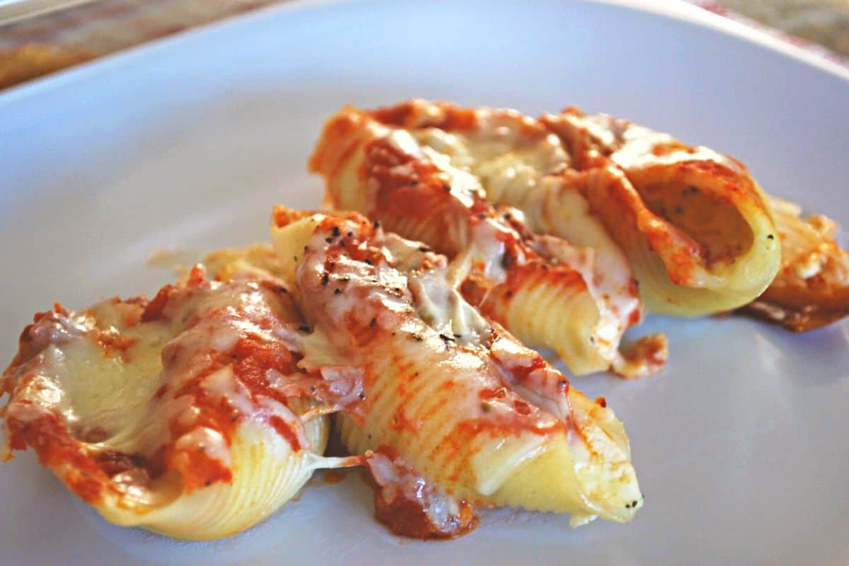 cheesy stuffed shells on white plate.