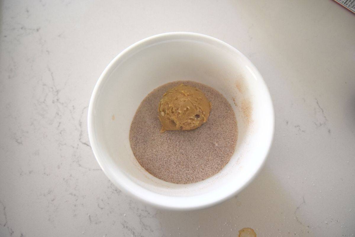 rolling a cookie in cinnamon sugar.