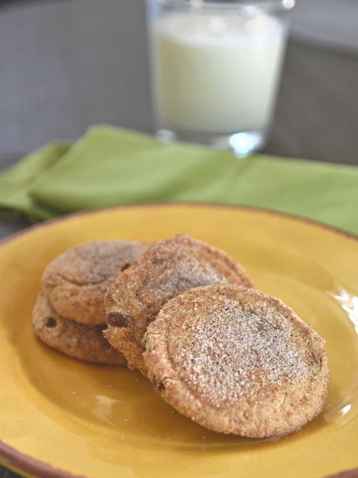 snickerdoodle cookies on yellow plate with glass of milk in the background.