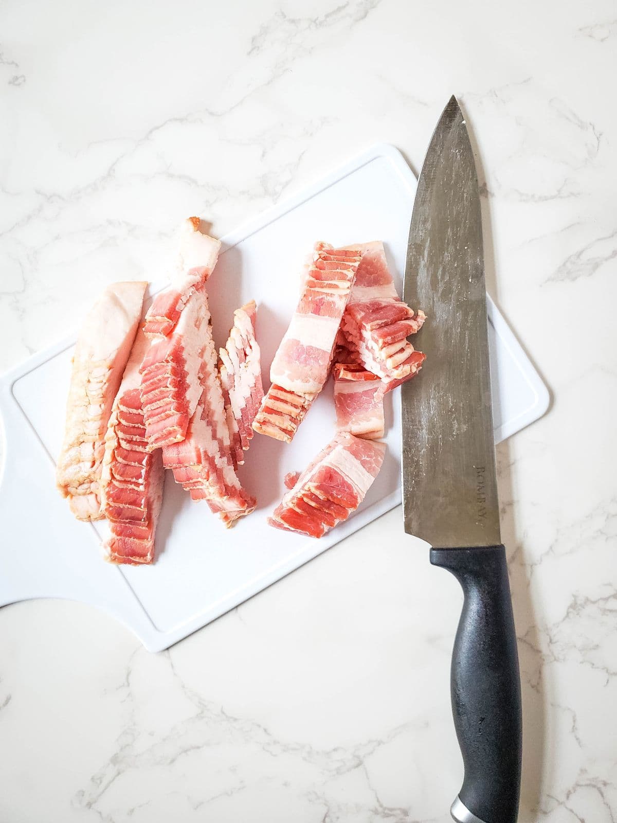 chopped bacon on cutting board with knife.