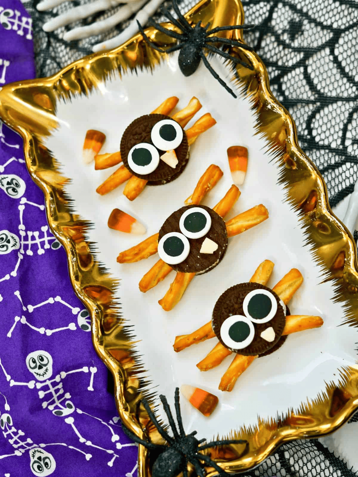 three oreo spider cookies made from oreo cookies and pretzels with candy eyes.