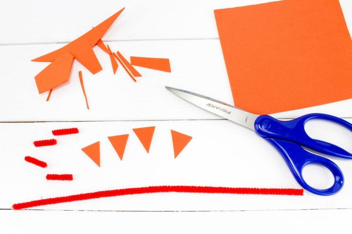 scissors  with orange triangles cut out and red pipe cleaner.