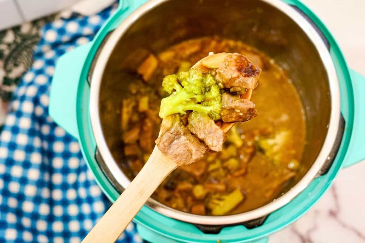 wooden spoon in instant pot with beef and broccoli.