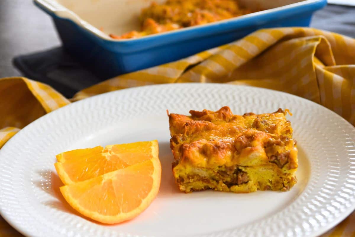 slice of breakfast casserole with bread on plate with orange slices