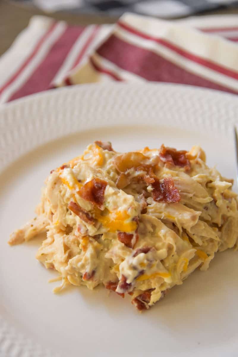 Overhead shot of crack chicken on a plate, showing melted cheese and bacon, with a red-striped napkin underneath.
