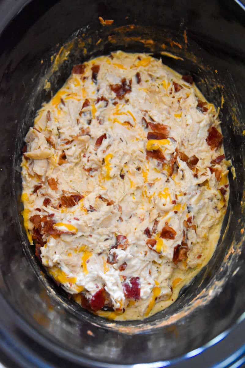 Creamy crack chicken in a slow cooker, filled with shredded chicken, melted cheese, and crispy bacon bits.