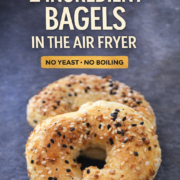 Two seeded bagels rest on a dark surface, highlighting the simplicity of this two ingredient bagels air fryer recipe.