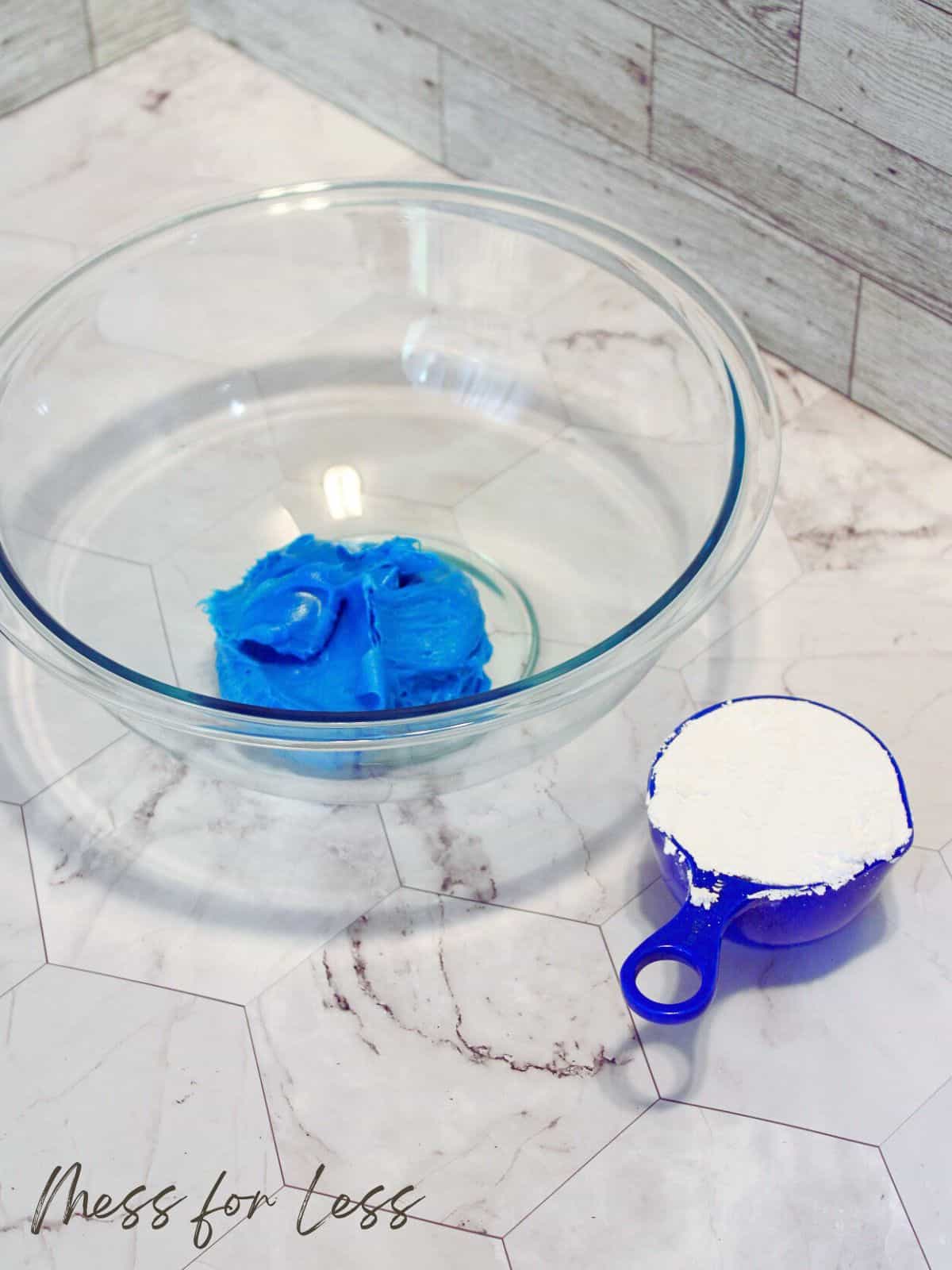 bowl with blue frosting and cup with powdered sugar