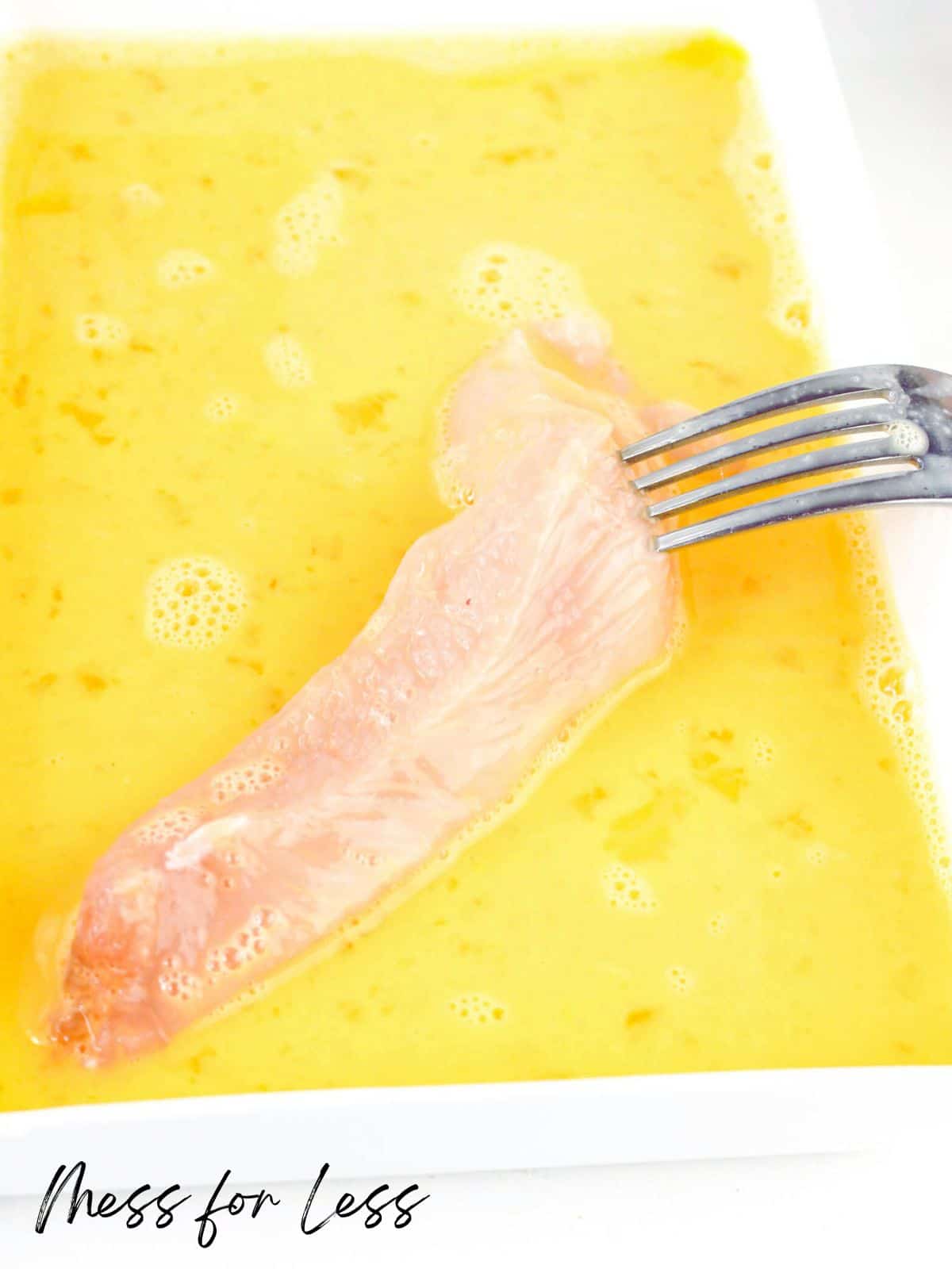 Dipping chicken breast in egg