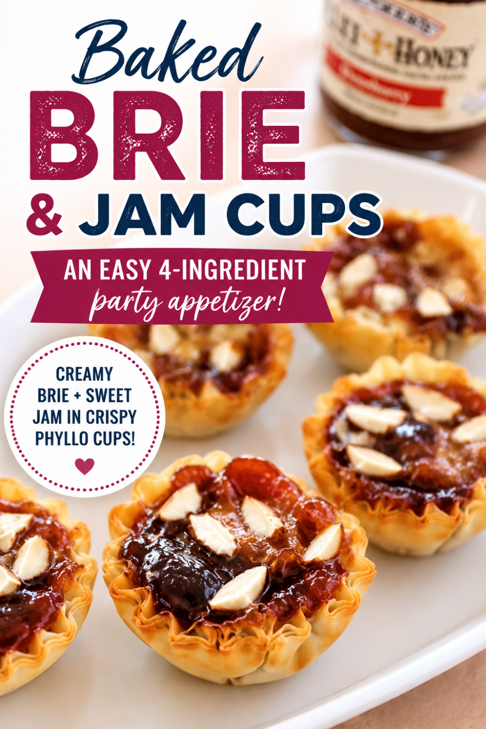Mini phyllo baked brie and jam cups are filled with creamy brie, sweet jam, and sliced almonds on a white dish, with a jar of jam nearby.