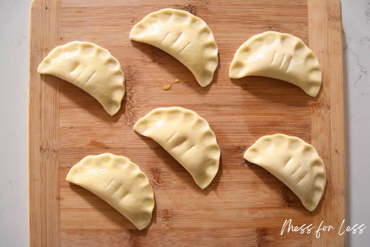 pie crust turnovers on cutting board with slits cut on top
